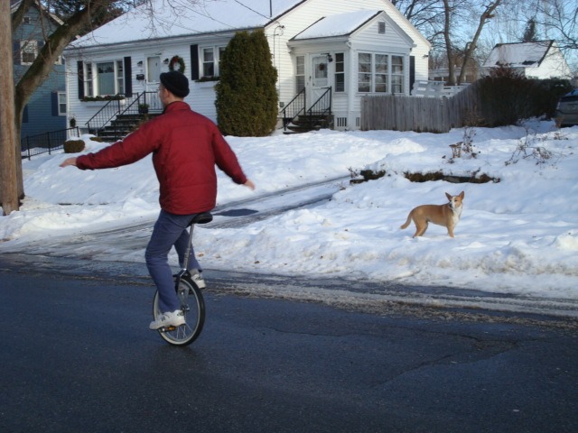 neil sattin rides a unicycle in winter while nola looks on amazed